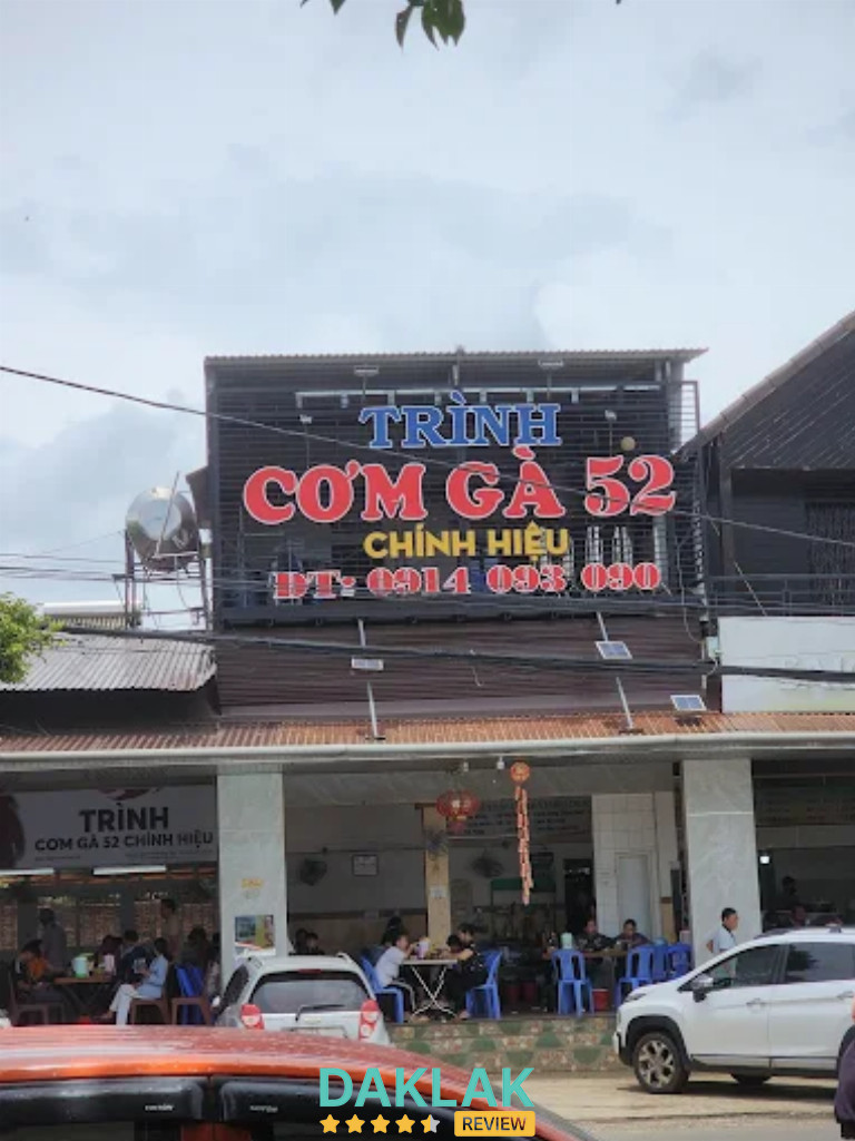 Mặt tiền quán Cơm Gà Trình 52 Chính Hiệu Ea Kar, bảng hiệu lớn nổi bật, khách ra vào tấp nập.”