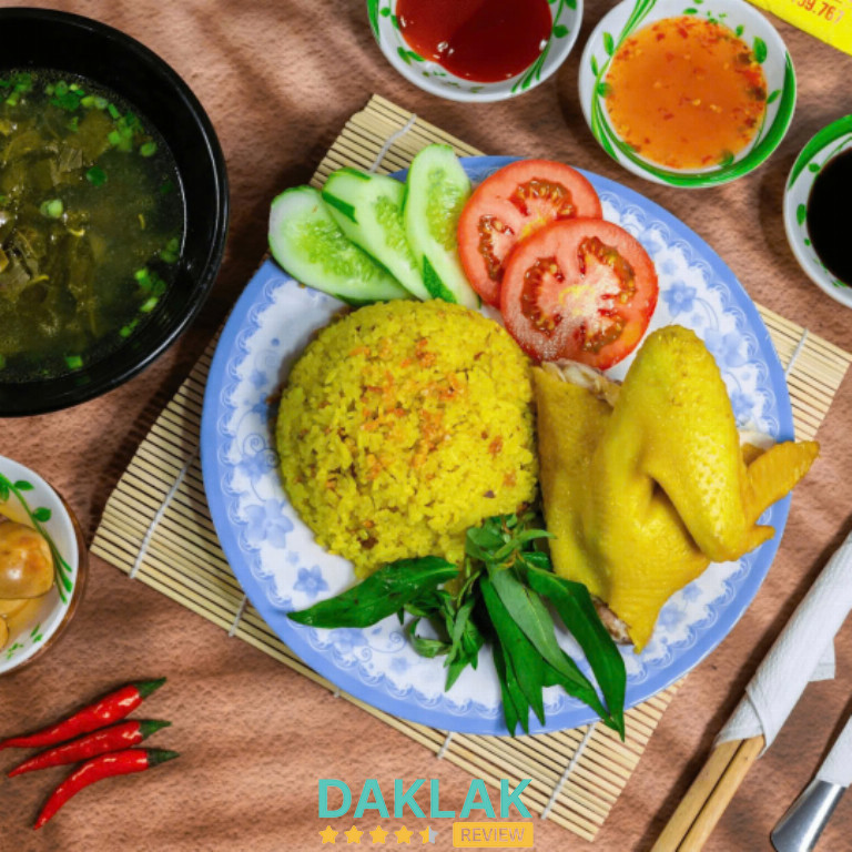 Dĩa cơm gà Trình 52 Chính Hiệu với cơm vàng đậm, gà ta luộc, rau thơm, dưa leo, cà chua và chén nước súp ăn kèm.”