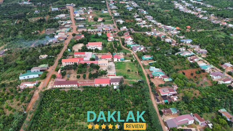 Toàn cảnh khu dân cư Buôn Hồ với nhà cửa thưa, nhiều cây xanh và đường đất đỏ đặc trưng.