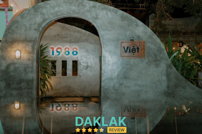 Cổng vào quán Cà Phê Việt 1988 với thiết kế cong độc đáo, không gian buổi tối tại Buôn Ma Thuột