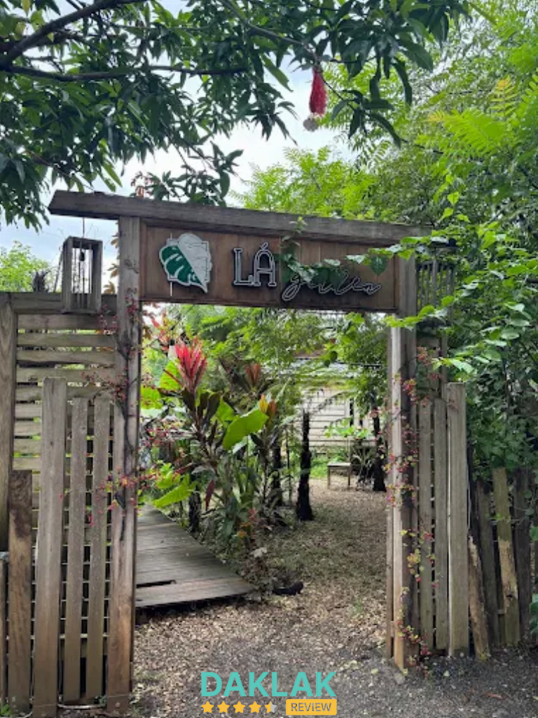 Cổng gỗ vào Lá Garden Coffee với lối đi xanh mát, nhiều cây cối tại Buôn Ma Thuột