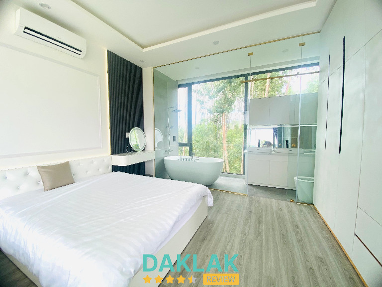 Phòng ngủ sáng rộng tại Làng Biệt Thự Trần Kim Huyền với bồn tắm kính và view rừng phía sau