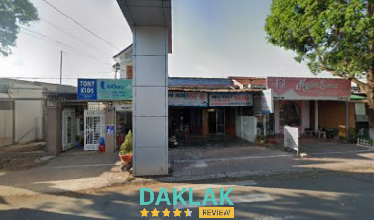 Dãy nhà mặt tiền có biển hiệu Nhà nghỉ Sao Mai cùng cửa hàng bên cạnh, chụp từ phía trước đường