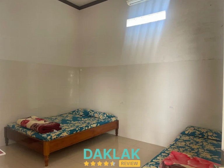 Phòng nghỉ có hai giường đơn, ga hoa văn và máy lạnh gắn trên tường