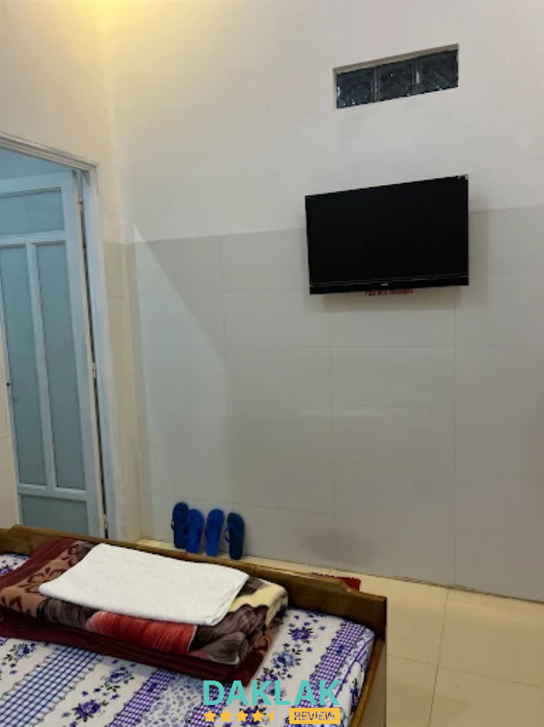 Phòng nghỉ có giường trải ga, chăn gấp sẵn và tivi treo tường đối diện giường