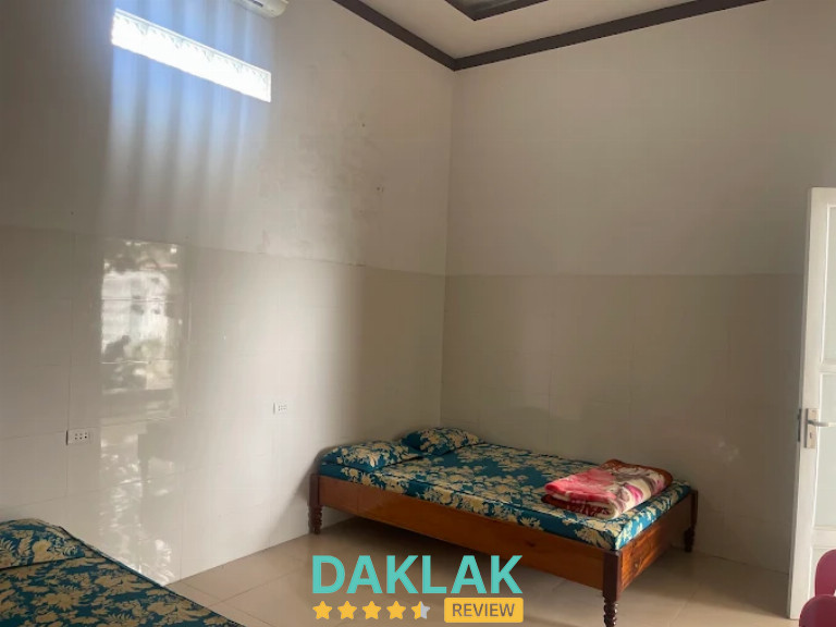 Phòng nghỉ có hai giường đơn trải ga hoa văn và cửa sổ cao lấy sáng