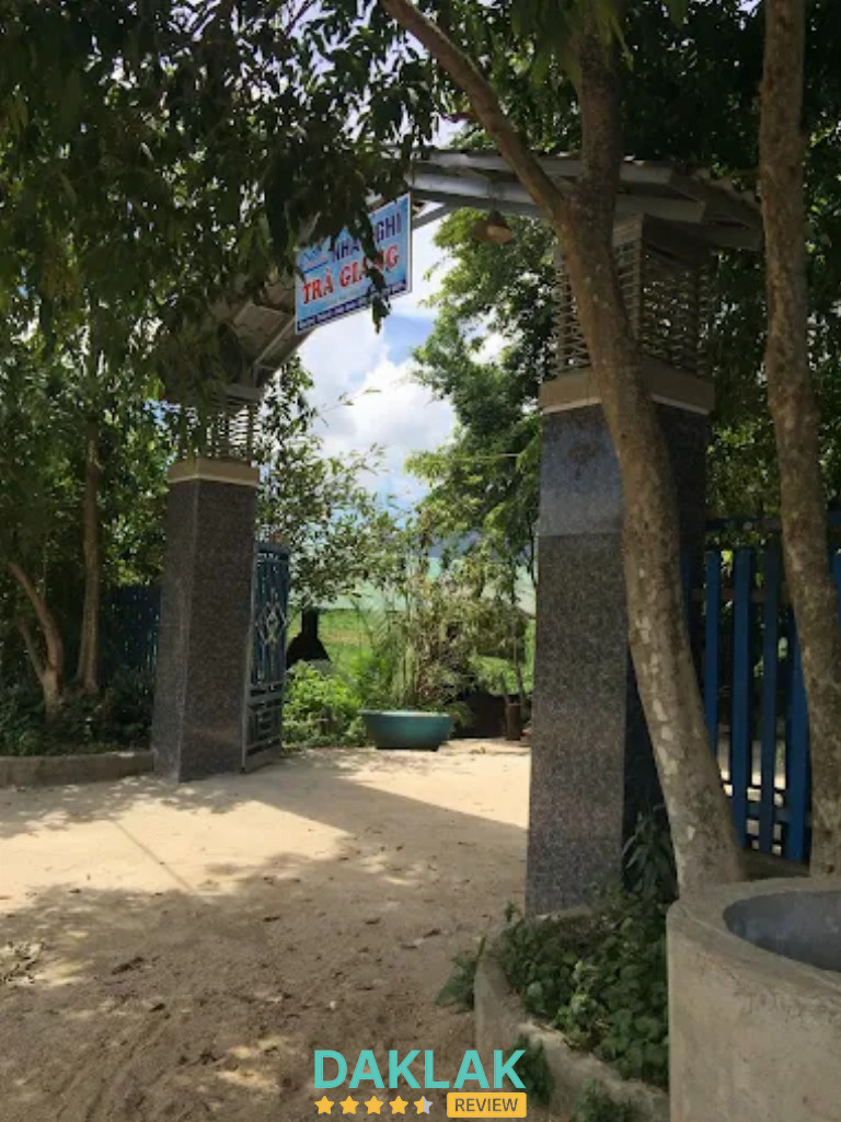 Cổng vào nhà nghỉ Trà Giang với trụ đá, bảng hiệu và lối đi rợp bóng cây