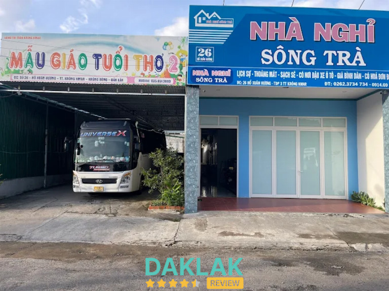 Mặt tiền nhà nghỉ Sông Trà với bảng hiệu lớn màu xanh, cửa kính và khu vực phía trước