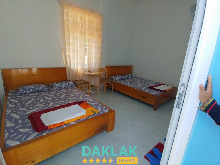 Phòng nghỉ nhà nghỉ Chân Đồi có hai giường gỗ, cửa sổ, bàn nhỏ và ánh sáng tự nhiê