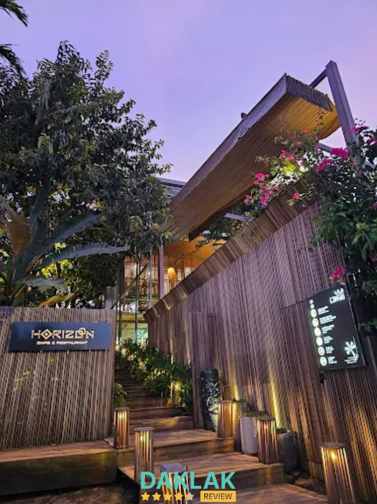 “Lối vào Horizon Cafe Buôn Ma Thuột với thiết kế gỗ và cây xanh vào buổi chiều tối”