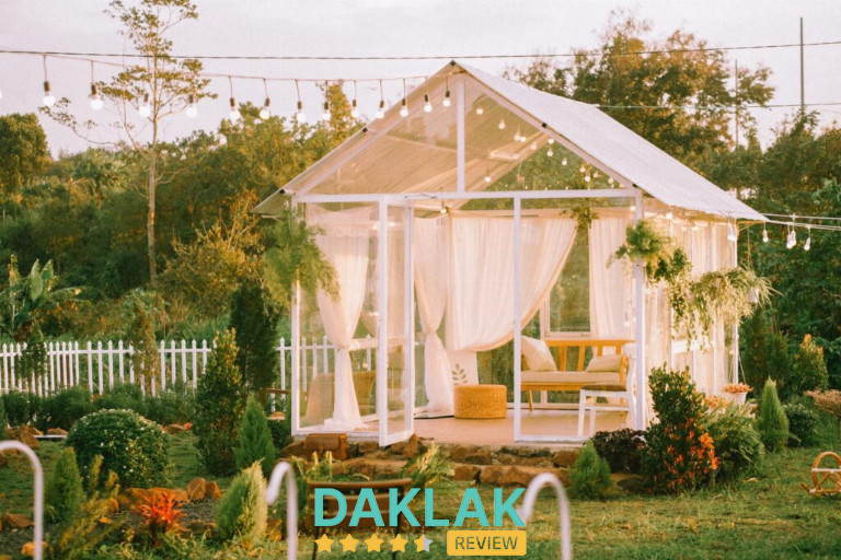 “Nhà kính trắng trong khu vườn Mộc Garden Buôn Ma Thuột với trang trí cây xanh và đèn dây”